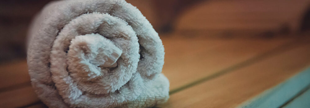 Traditional wooden sauna for relaxation with a set of clean towels. Good quality service in a classical steam sauna. First-class amenities of an eco-designed sauna. A towel put for using in sauna.